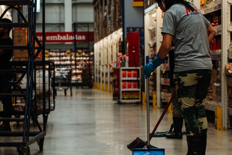 A relief cleaner in gloves mopping the floor of a large retail warehouse.