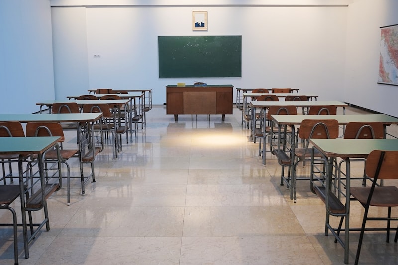 An empty, tidy classroom with rows of desks and a blackboard.