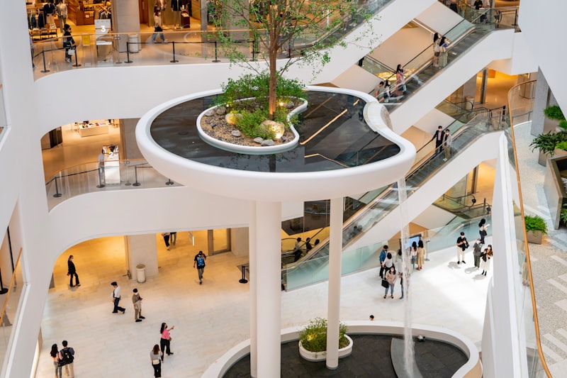 A bright, spotless multi-level shopping centre atrium with escalators.