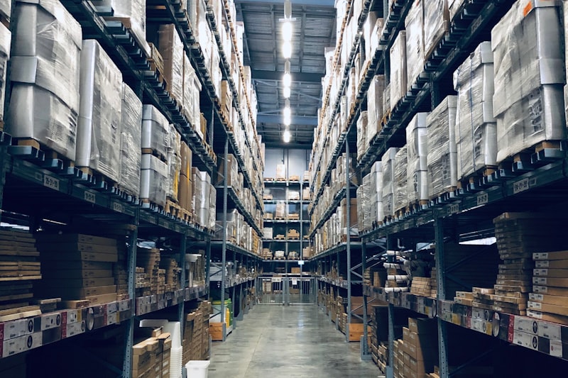 A clean warehouse aisle between tall racking stacked with wrapped pallets.