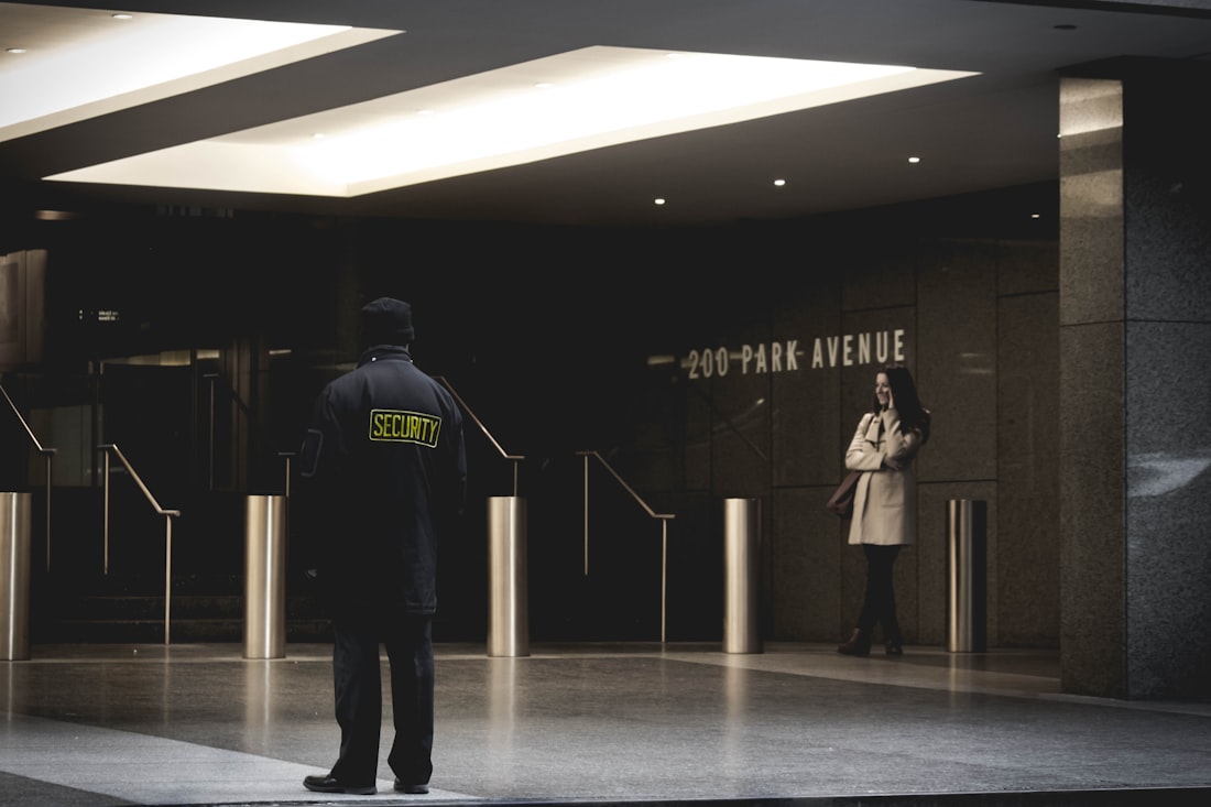 A uniformed security officer posted at the entrance of a commercial office building.